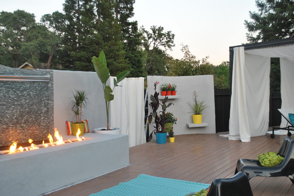 Inspiration for a mid-sized tropical backyard deck remodel in Sacramento with a fire pit and a pergola