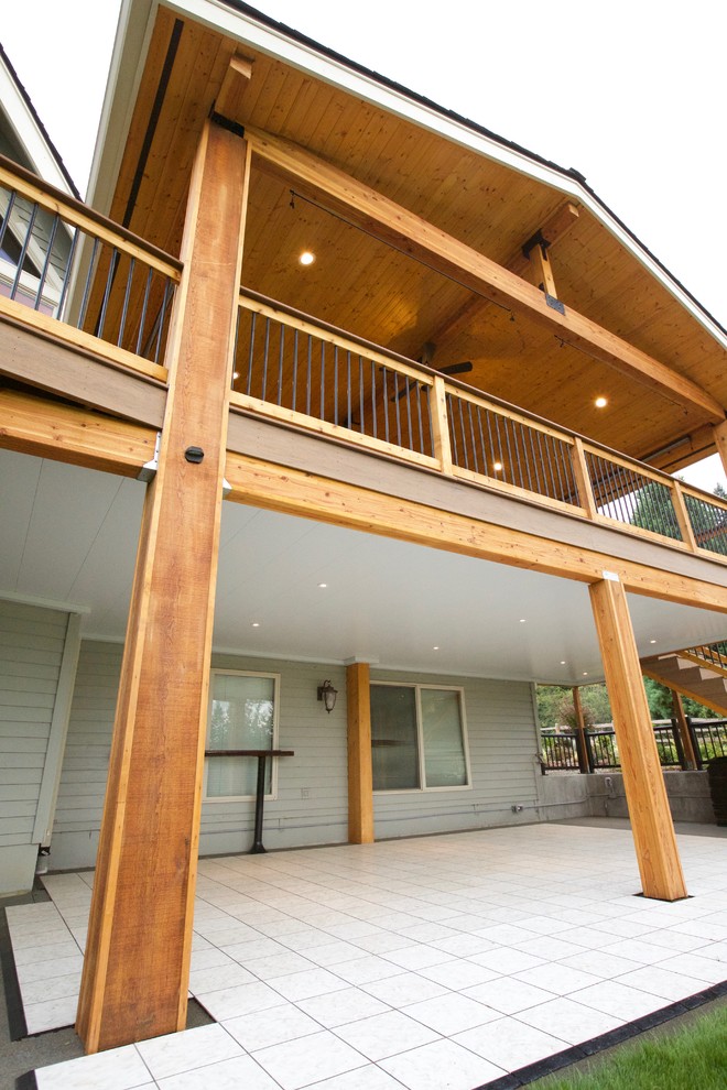 Photo of a large rustic back terrace in Seattle with a roof extension.