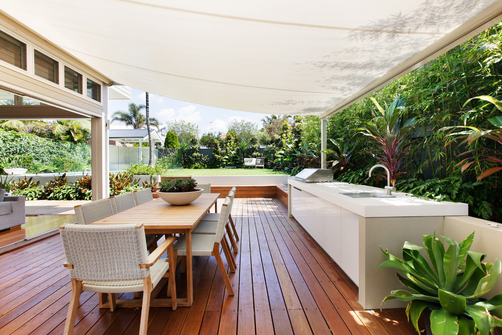 Example of a mid-sized transitional side yard outdoor kitchen deck design in Sydney with an awning