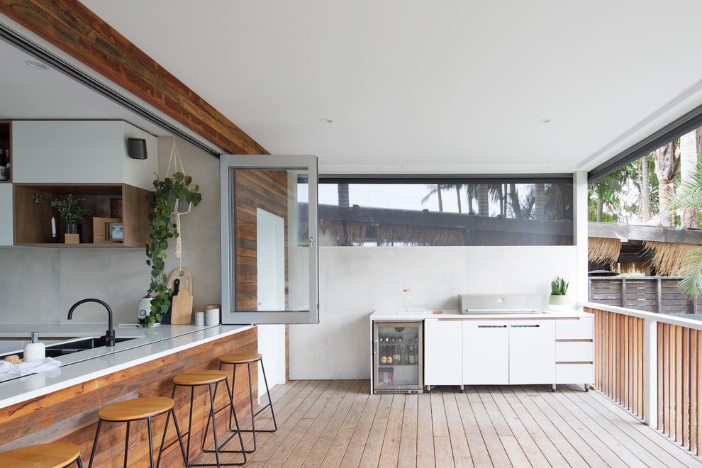 Cette photo montre une grande terrasse arrière tendance avec une extension de toiture et une cuisine d'été.