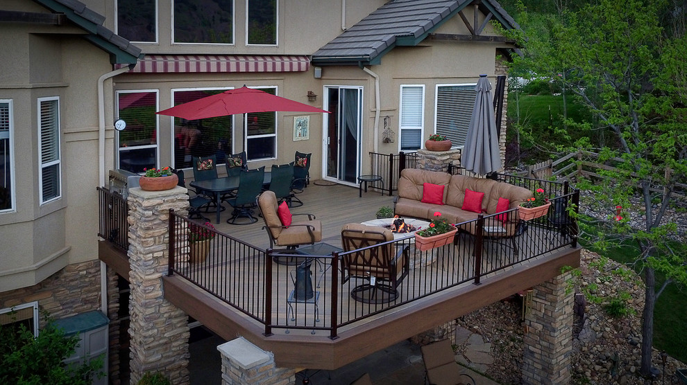 Diseño de terraza clásica grande en patio trasero con brasero, toldo y barandilla de metal