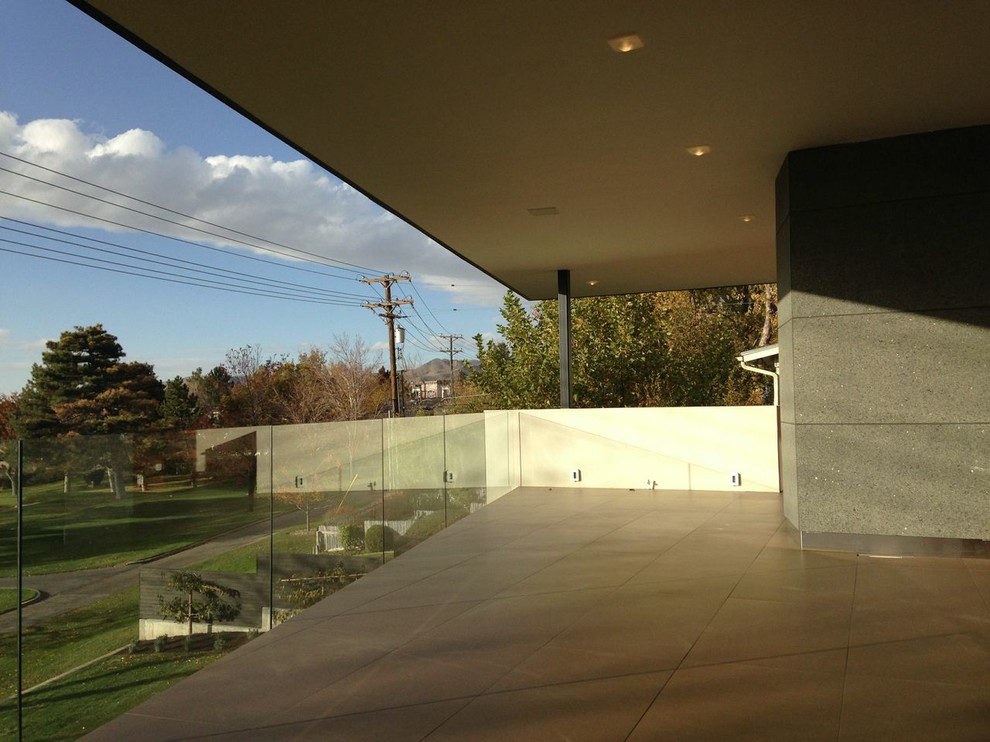 Cette image montre une très grande terrasse arrière minimaliste avec une extension de toiture.
