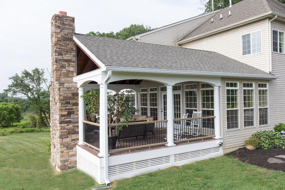 Idée de décoration pour une grande terrasse arrière tradition avec un foyer extérieur et une extension de toiture.