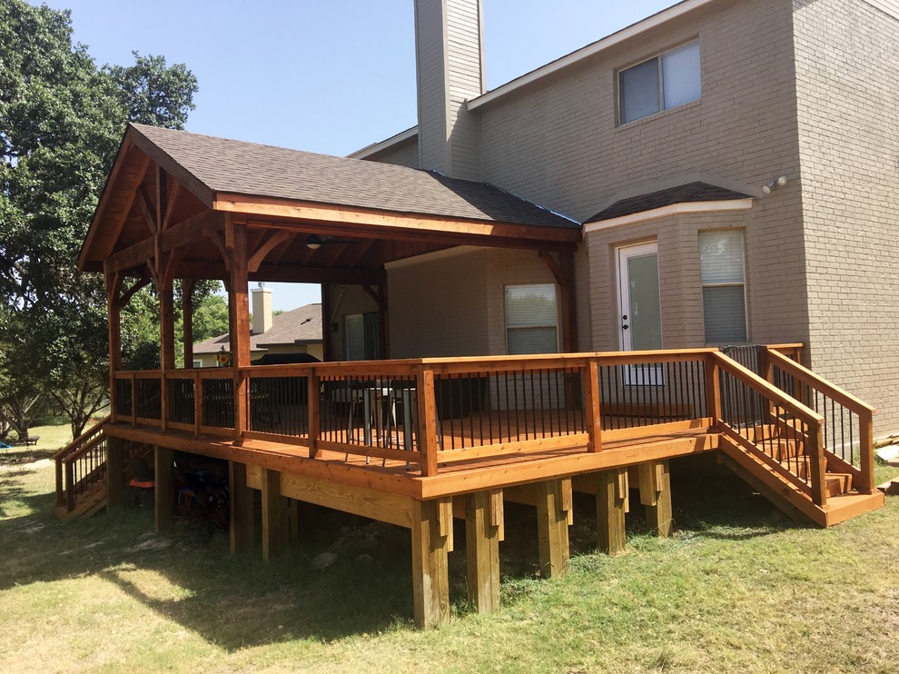 Large mountain style backyard deck photo in Other with a roof extension