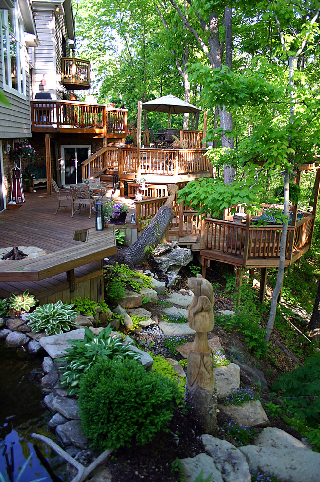 Example of a huge classic backyard deck design in Other with a fire pit and a pergola