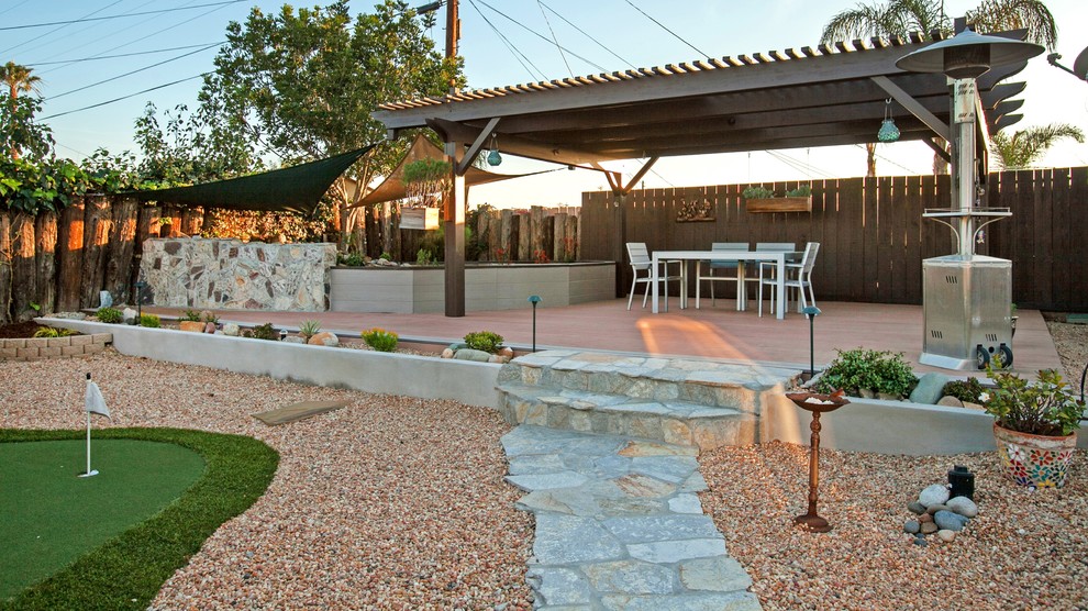 This is an example of a medium sized back terrace in Los Angeles with a pergola and a water feature.