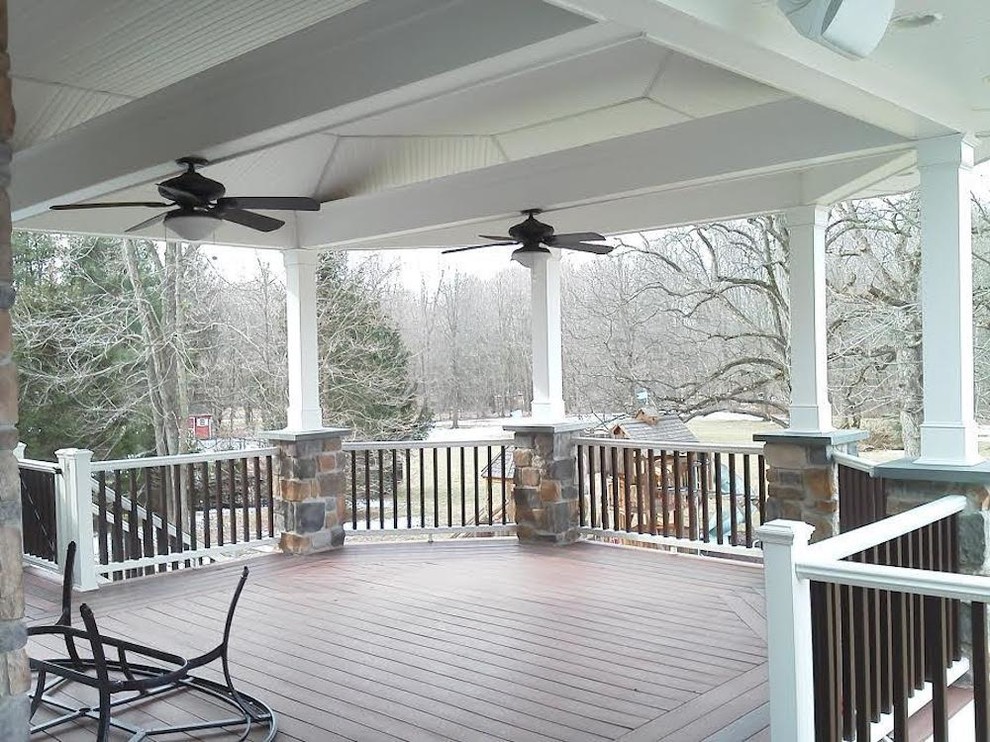 Example of a large classic backyard deck design in New York with a roof extension