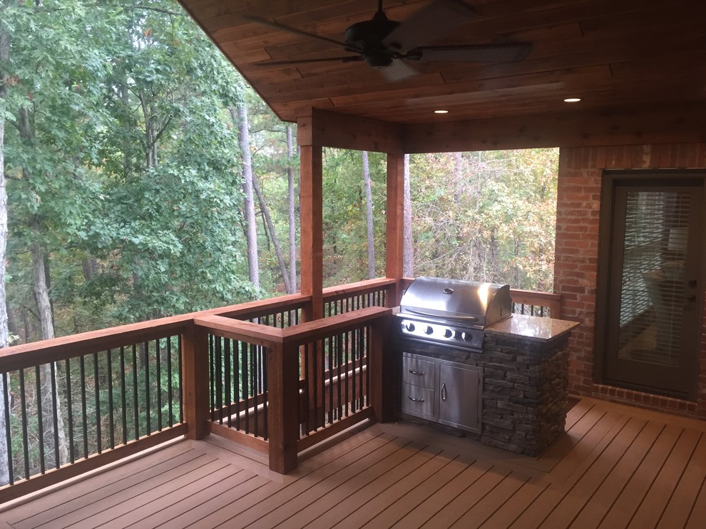 Inspiration for a large rustic backyard outdoor kitchen deck remodel in Little Rock with a roof extension