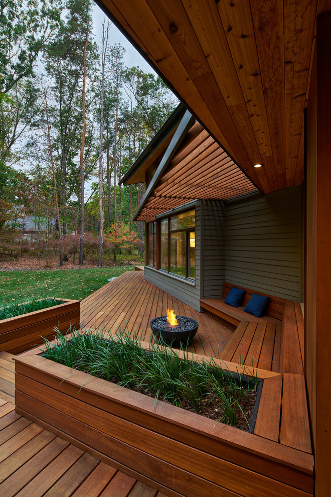 Cette image montre une terrasse design avec un foyer extérieur et une extension de toiture.