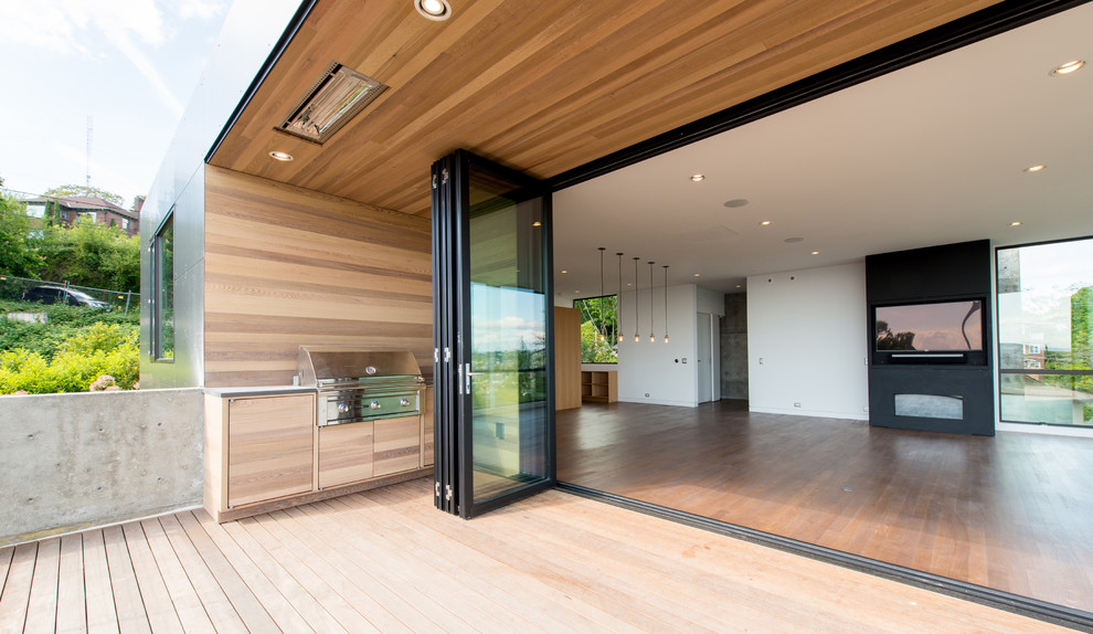 Cette photo montre une grande terrasse arrière moderne avec une cuisine d'été et une extension de toiture.