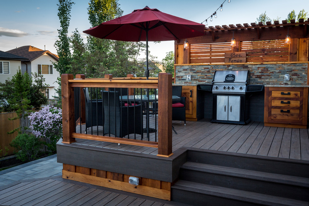 Large traditional back terrace in Calgary with an outdoor kitchen and a pergola.