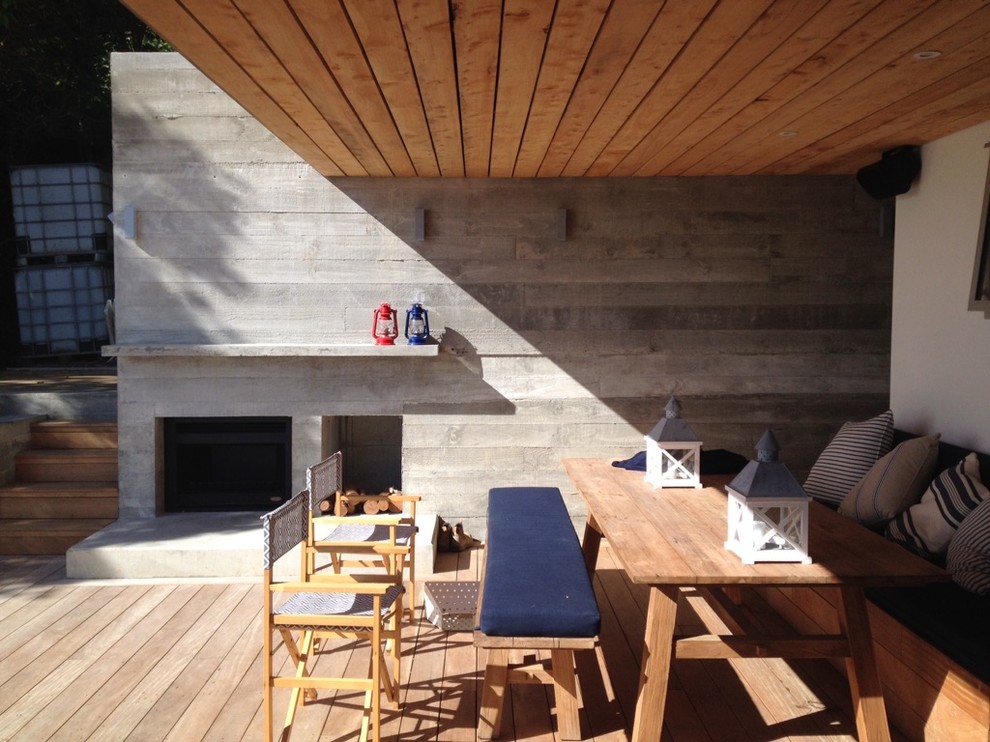 Cette photo montre une terrasse arrière tendance de taille moyenne avec un foyer extérieur et une extension de toiture.