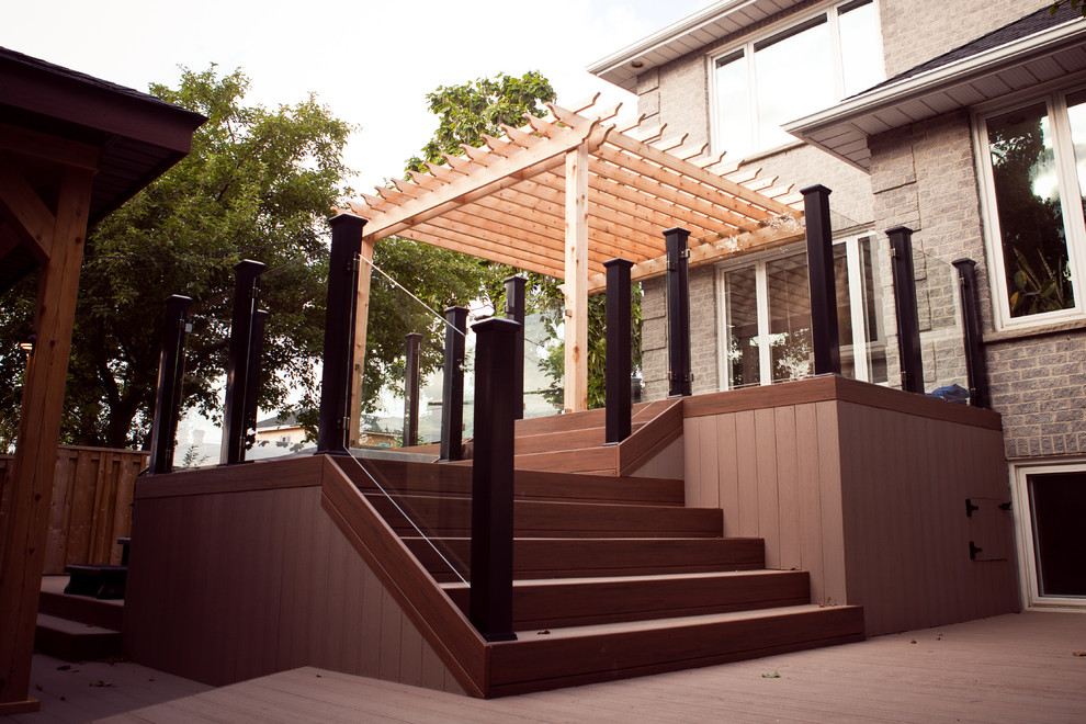 Inspiration for a large contemporary backyard water fountain deck remodel in Toronto with a pergola