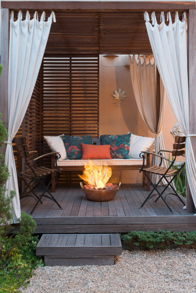 Photo of a large world-inspired back ground level wood railing terrace in Miami with a fireplace and a pergola.
