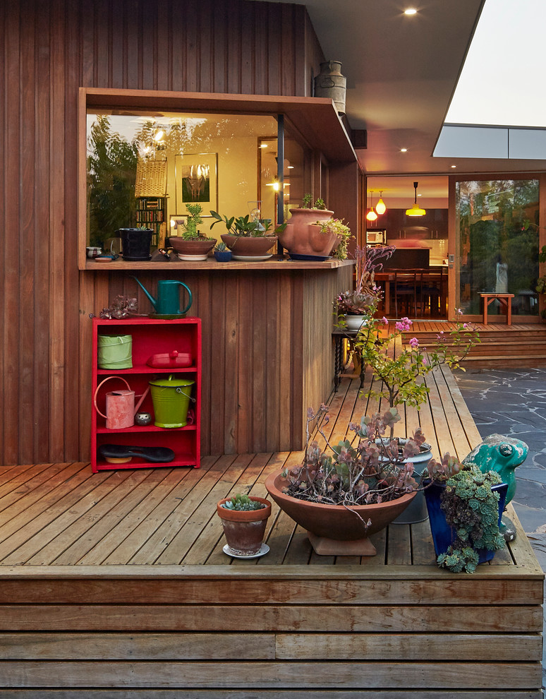 Inspiration pour une terrasse avec des plantes en pots arrière chalet de taille moyenne avec une extension de toiture.