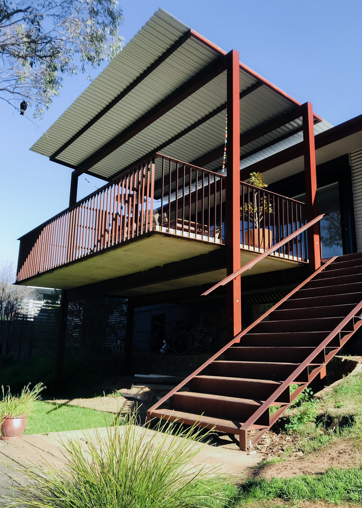 Inspiration pour une grande terrasse arrière design avec une extension de toiture.