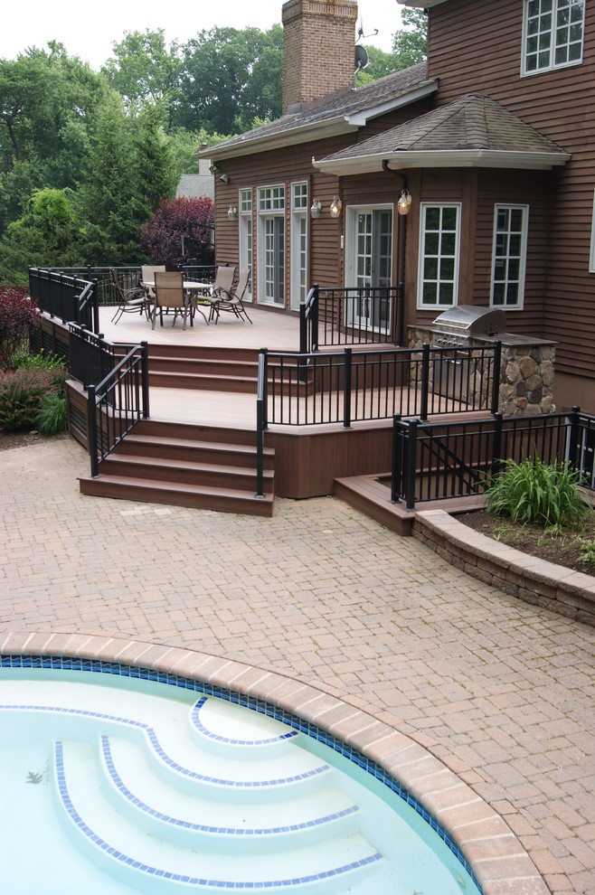 Large elegant backyard outdoor kitchen deck photo in New York