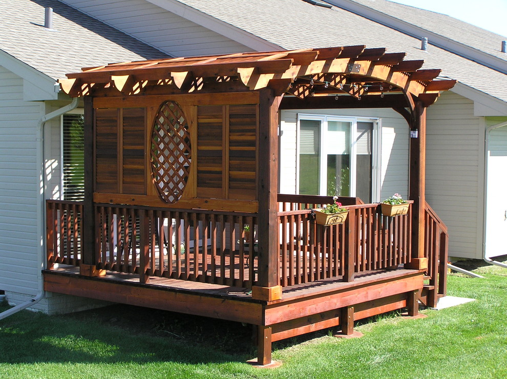 This is an example of a medium sized back terrace in Omaha with a pergola.