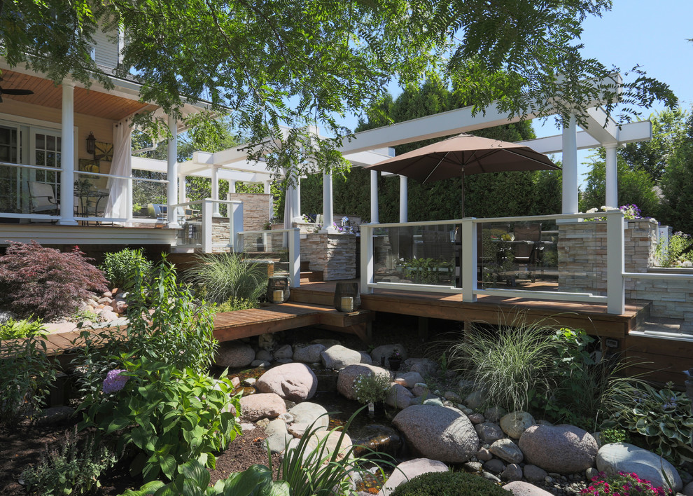 This is an example of an expansive classic back terrace in Chicago with an outdoor kitchen and a pergola.