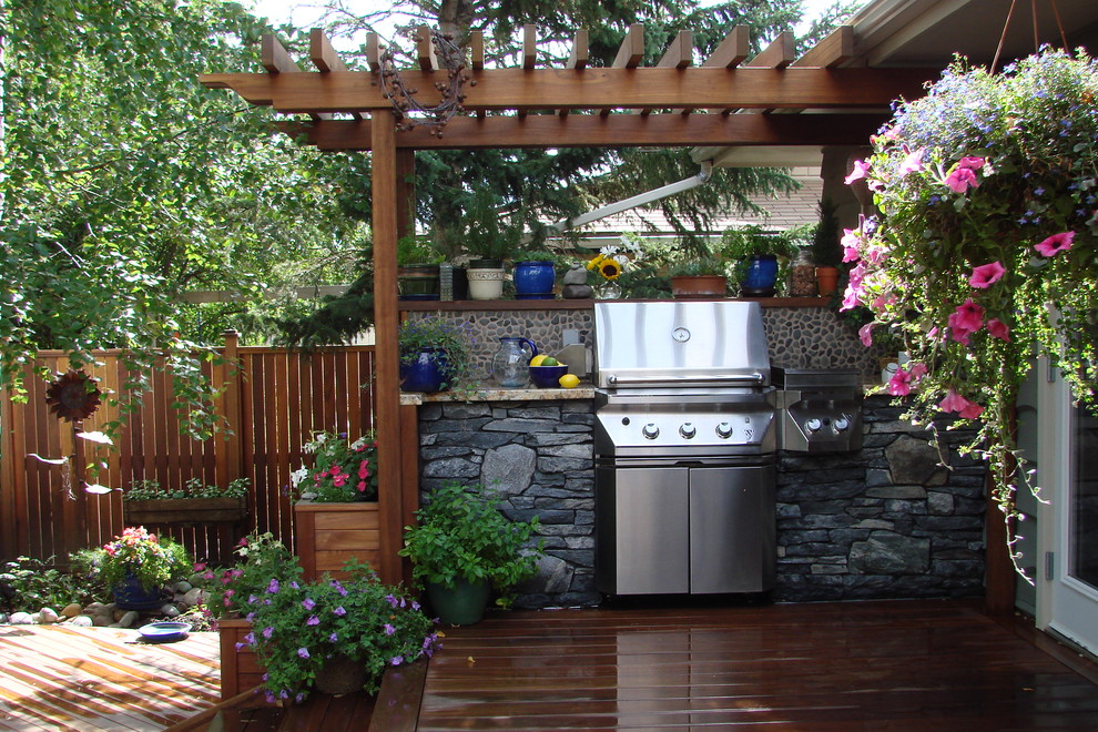 Outdoor kitchen deck - traditional backyard outdoor kitchen deck idea in Calgary with a pergola