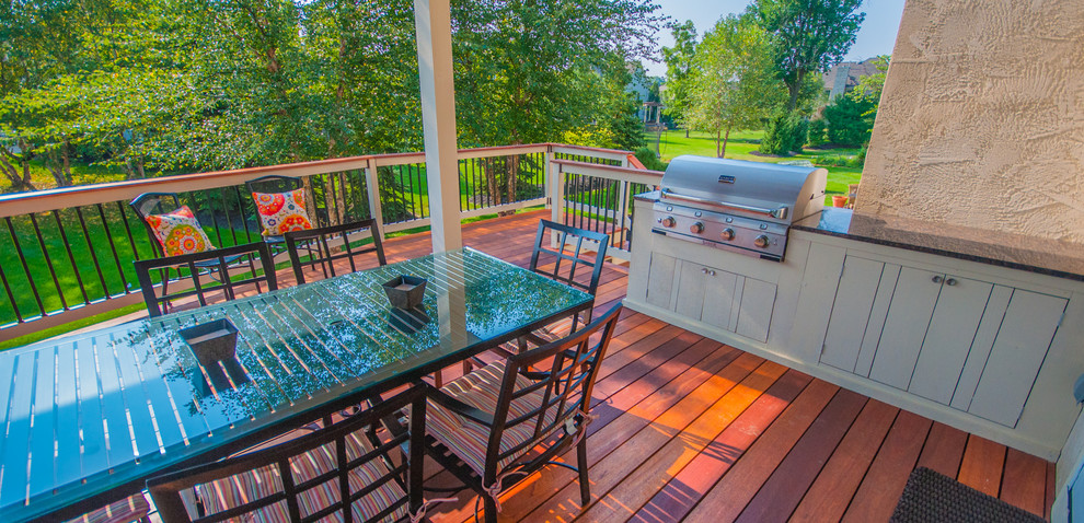 Example of a large transitional backyard deck design in Columbus with a roof extension and a fire pit