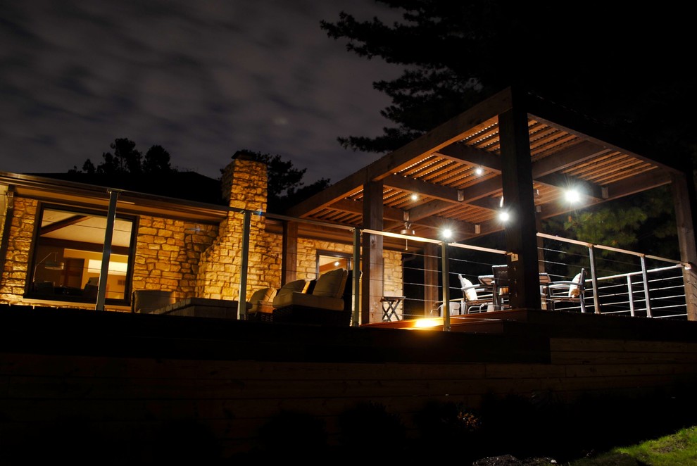 Cette image montre une grande terrasse arrière design avec un foyer extérieur et une pergola.