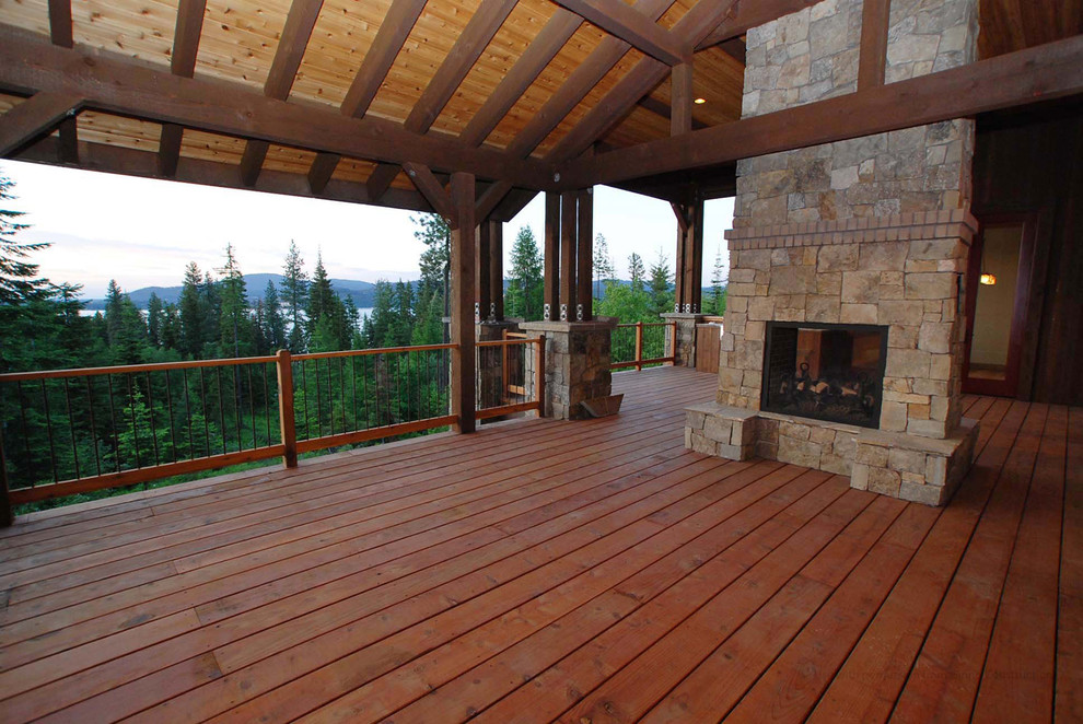 This is an example of a large rustic back terrace in Seattle with a fire feature and a roof extension.