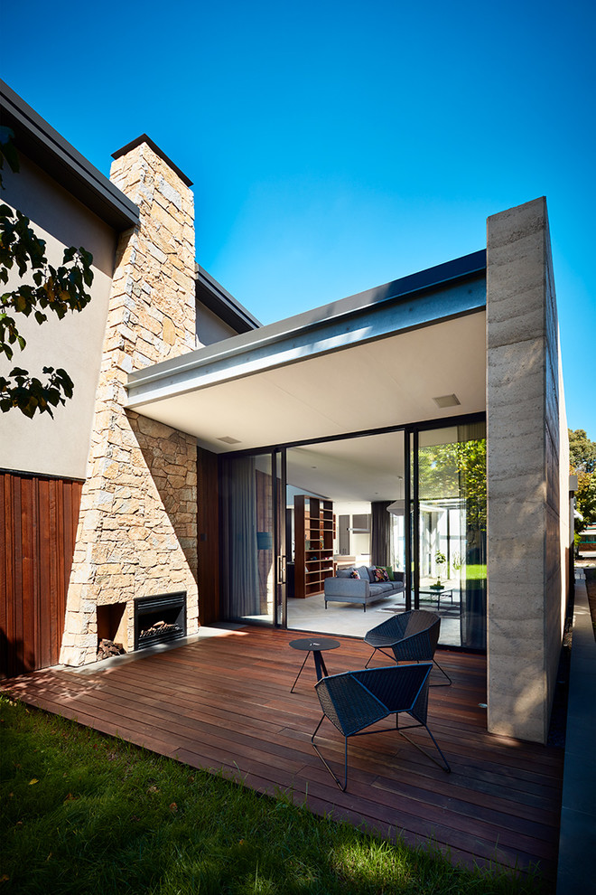 Cette photo montre une terrasse arrière tendance avec un foyer extérieur et une extension de toiture.