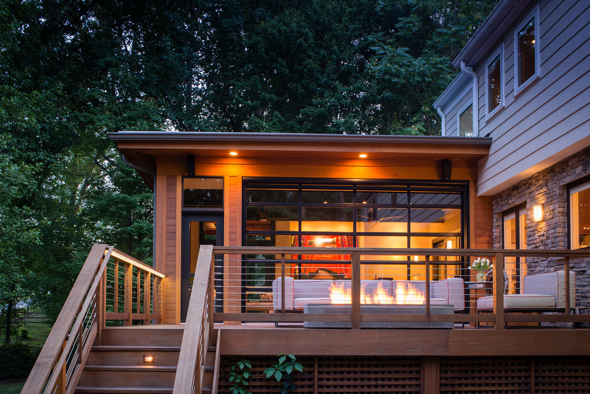 Example of a mid-sized transitional backyard deck design in DC Metro with a fire pit and a roof extension