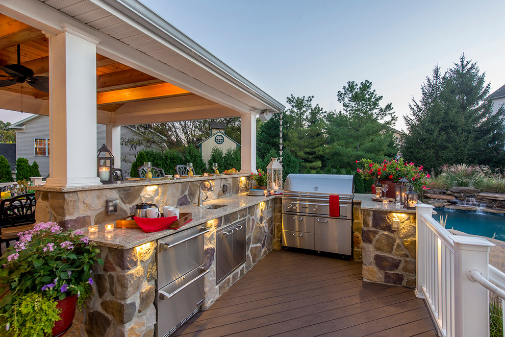 Cette photo montre une terrasse arrière chic de taille moyenne avec une cuisine d'été et une extension de toiture.