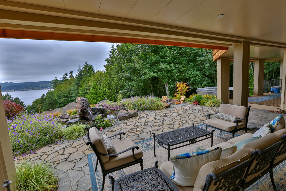 Foto di un grande patio o portico american style dietro casa con un focolare, pavimentazioni in pietra naturale e nessuna copertura