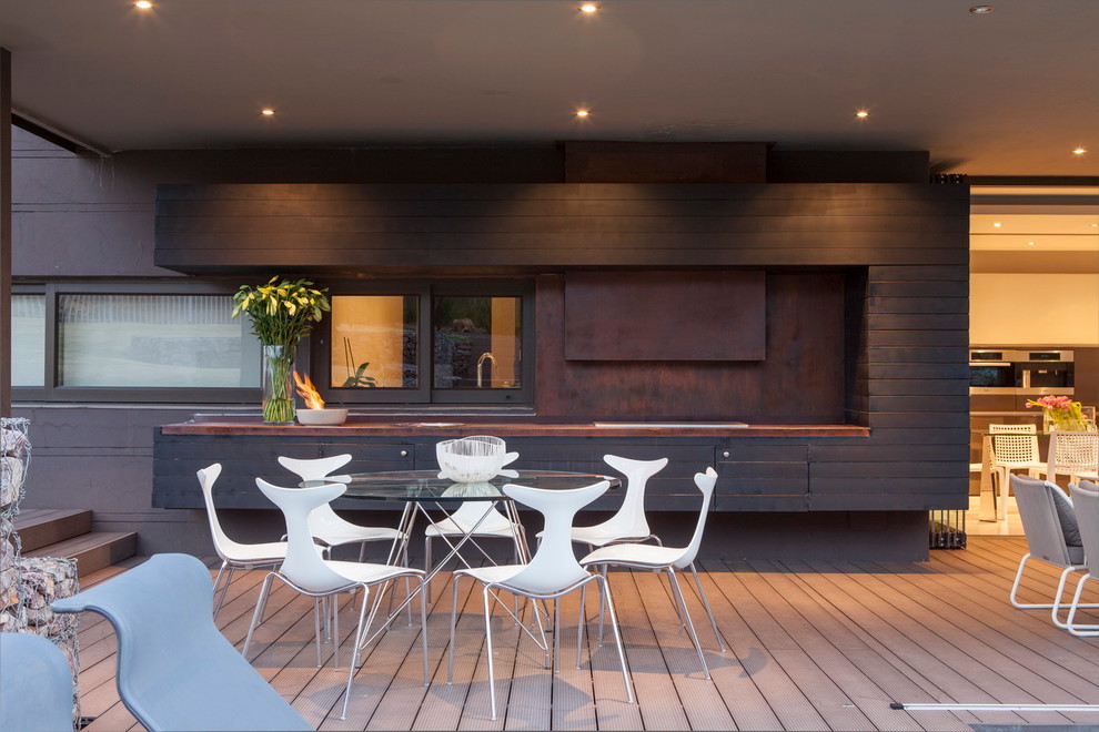 На фото: терраса на заднем дворе в современном стиле с летней кухней и навесом с