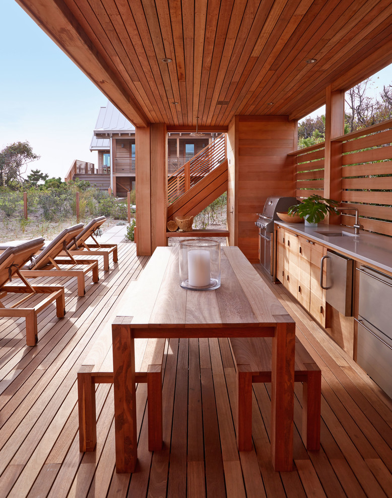 This is an example of a large beach style back terrace in New York with an outdoor kitchen and a roof extension.