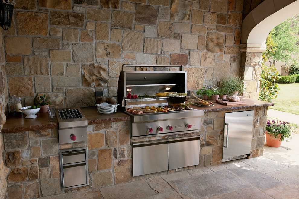 Example of a tuscan backyard concrete paver patio kitchen design in Cleveland