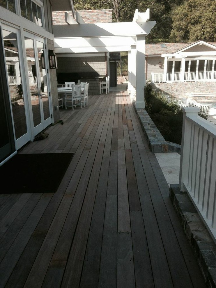 Modelo de terraza rústica grande en patio trasero con cocina exterior y pérgola