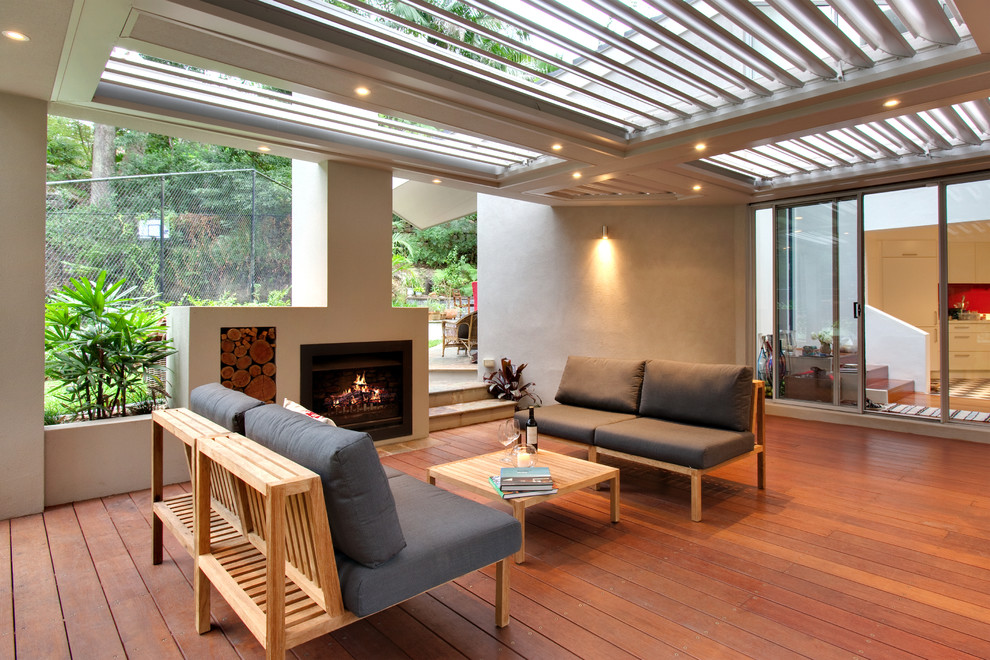 Idées déco pour une terrasse arrière contemporaine de taille moyenne avec un foyer extérieur et une extension de toiture.