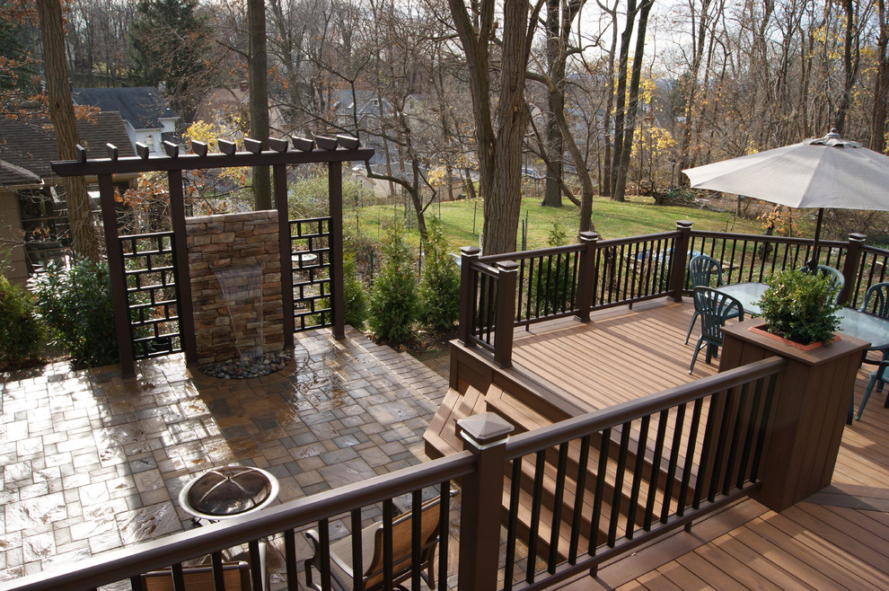 Example of a mid-sized trendy backyard water fountain deck design in New York with a pergola