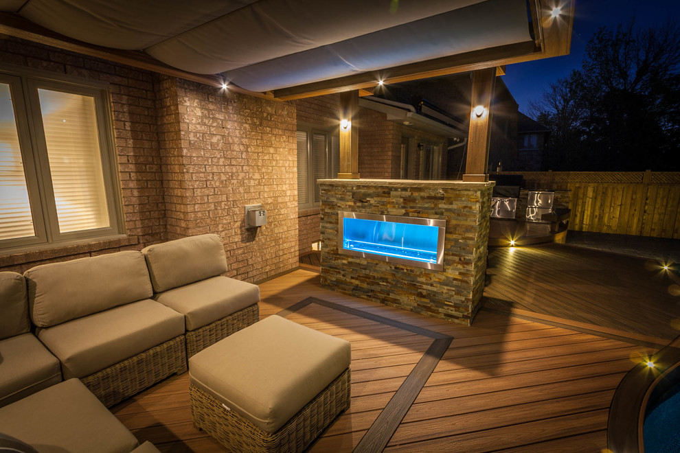 Foto de terraza contemporánea de tamaño medio en patio trasero con cocina exterior y toldo