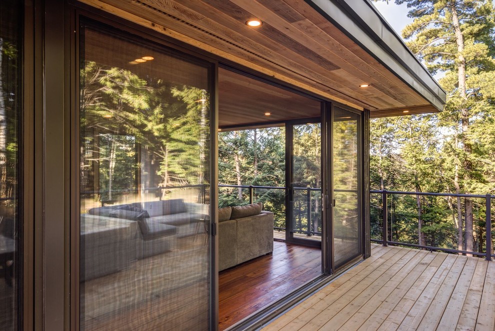 Inspiration for a mid-sized contemporary side yard deck remodel in Other with a roof extension