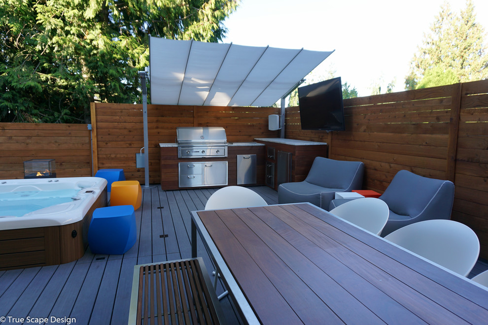 Diseño de terraza minimalista de tamaño medio en patio trasero con toldo y cocina exterior