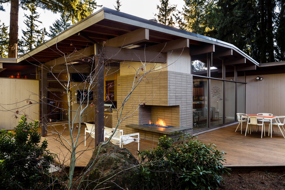 Inspiration for a mid-sized 1950s backyard deck remodel in Portland with a fire pit and a roof extension