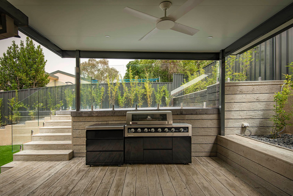 Ejemplo de terraza actual grande en patio trasero con cocina exterior, pérgola y barandilla de vidrio
