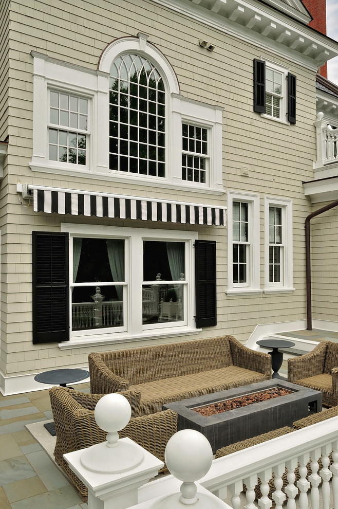 Inspiration pour une très grande terrasse arrière traditionnelle avec un foyer extérieur et un auvent.