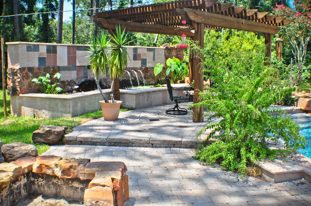 Imagen de terraza mediterránea de tamaño medio en patio trasero con fuente y pérgola