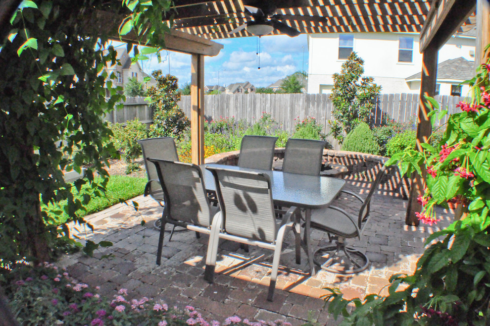 Imagen de patio mediterráneo de tamaño medio en patio trasero con brasero y pérgola