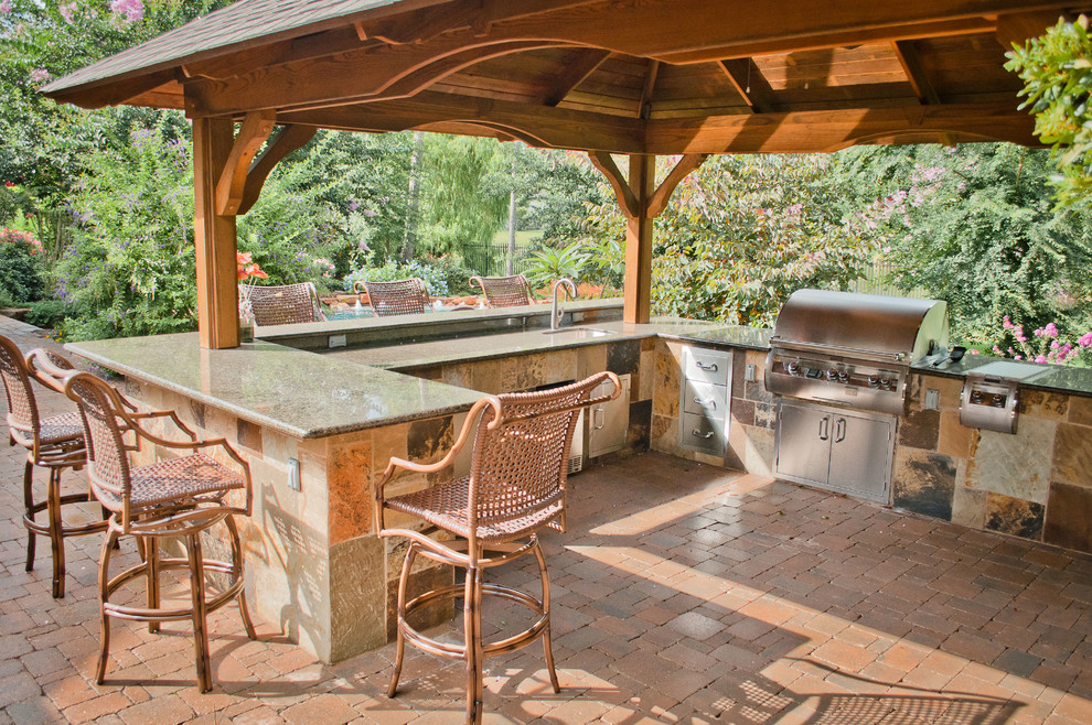 This is an example of a large mediterranean back patio in Houston with an outdoor kitchen and a pergola.