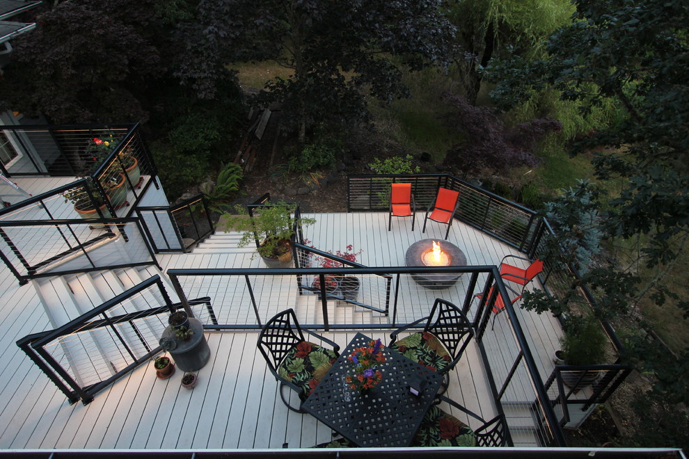 Inspiration pour une grande terrasse arrière minimaliste avec un foyer extérieur et aucune couverture.
