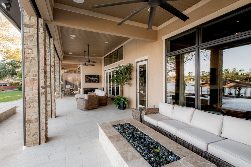 This is an example of a large modern back terrace in Houston with a fire feature and a roof extension.