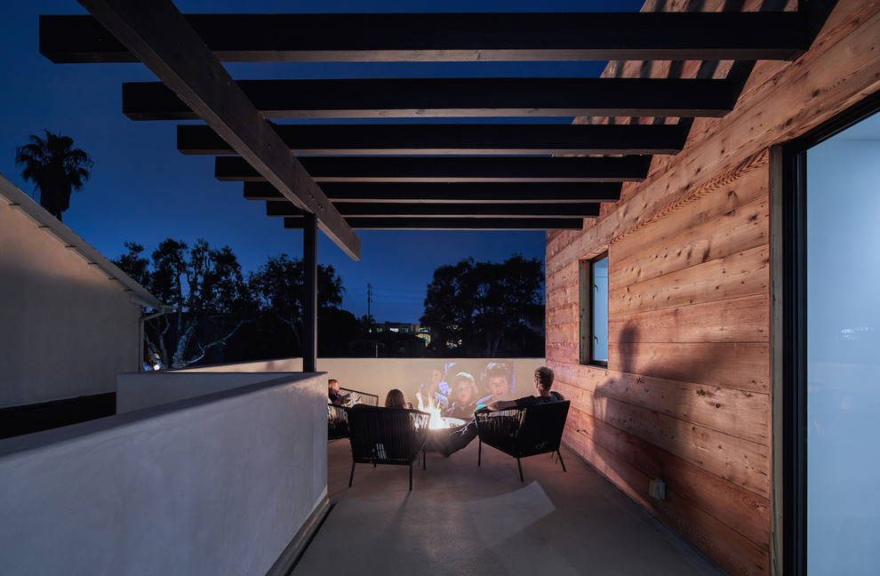 Esempio di una terrazza minimalista di medie dimensioni e sul tetto con un focolare e una pergola