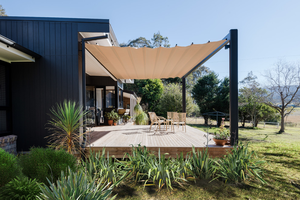 This is an example of a large retro back terrace in Wollongong with an awning and a bar area.
